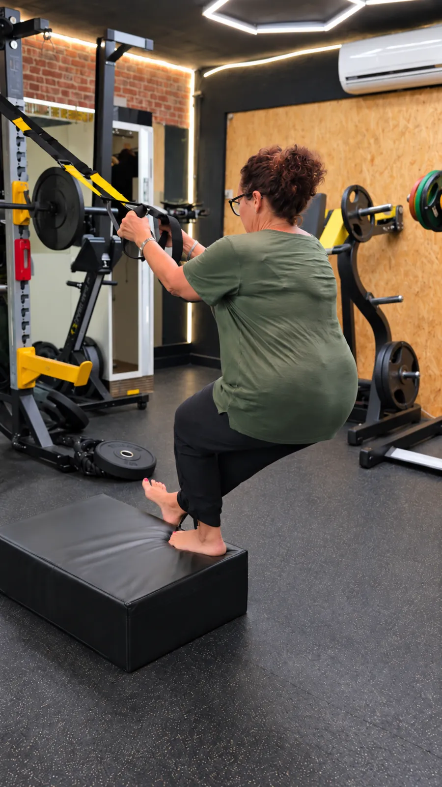 Une adhérente fait une fente sur un step, dans la salle du centre Platinium Training