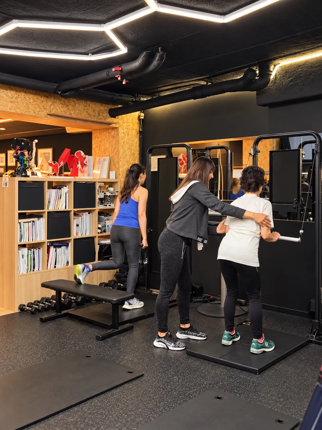 Une coach accompagne une adhérente pendant un exercice, dans la salle du centre Platinium Training