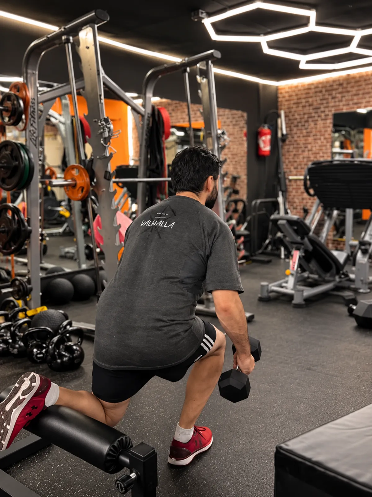 Un adhérent fait une fente avec des haltères dans l’espace musculation du centre Platinium Training