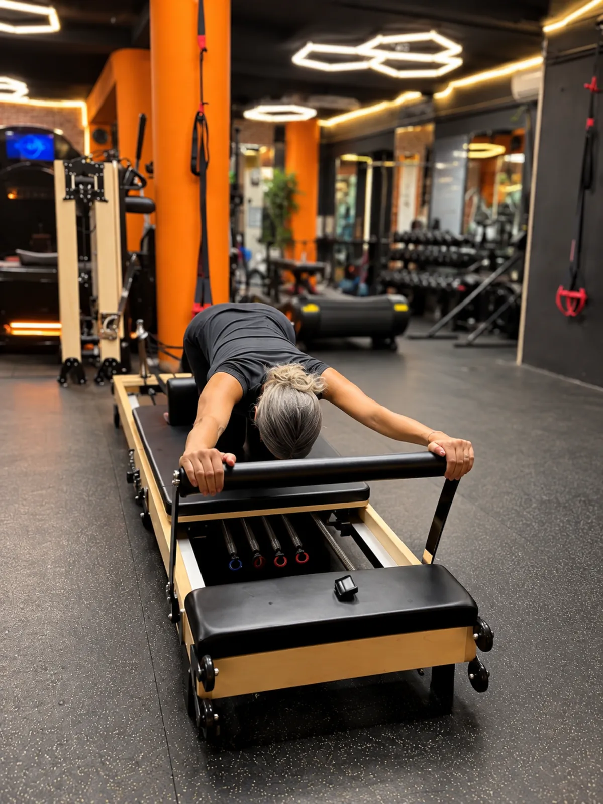 Une adhérente sur le Pilates Reformer dans la salle du centre Platinium Training, sous les néons hexagonaux