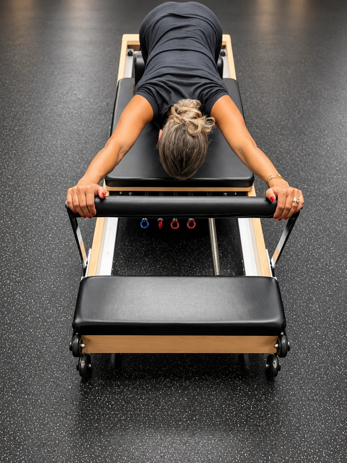 Une adhérente allongée sur le ventre sur le Pilates Reformer, vue du dessus, au centre Platinium Training