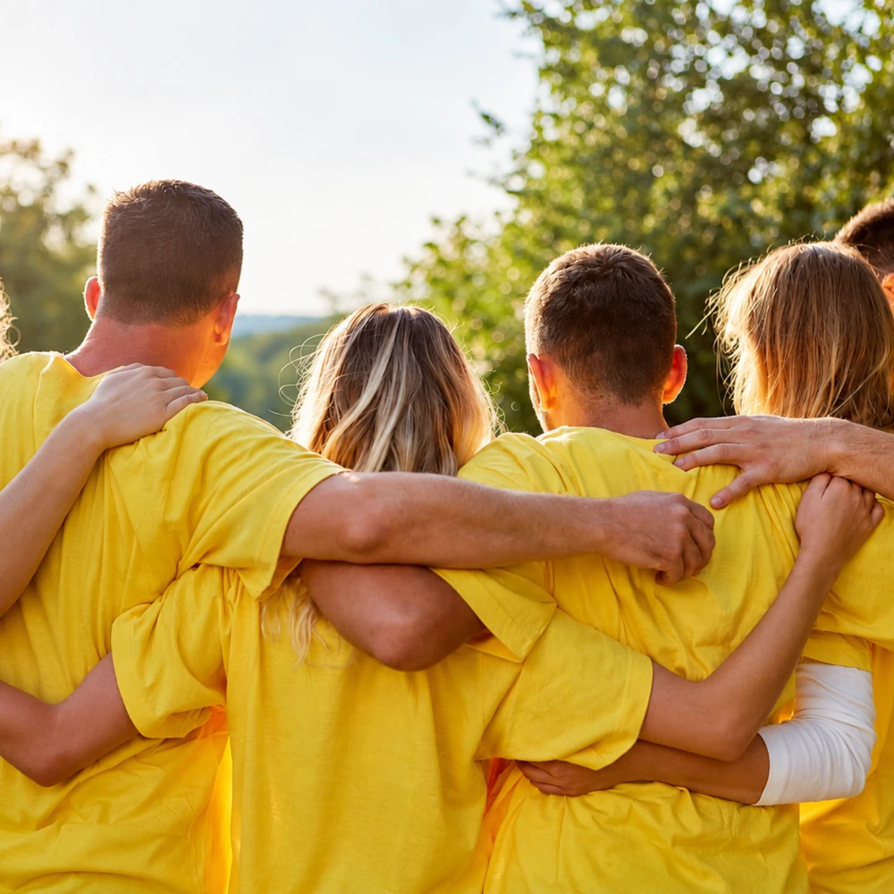 Une équipe en t-shirts jaunes se tient par les épaules, après un défi collectif